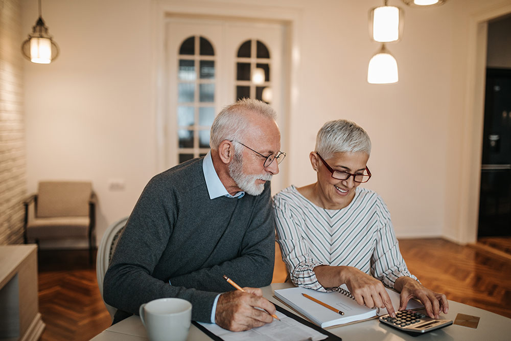 Senior couple looking over budget and expenses to save money for senior living