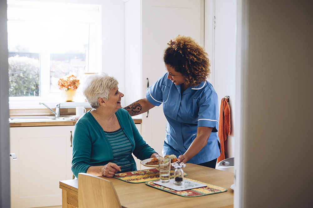 Senior woman getting food from caregiver in senior living community